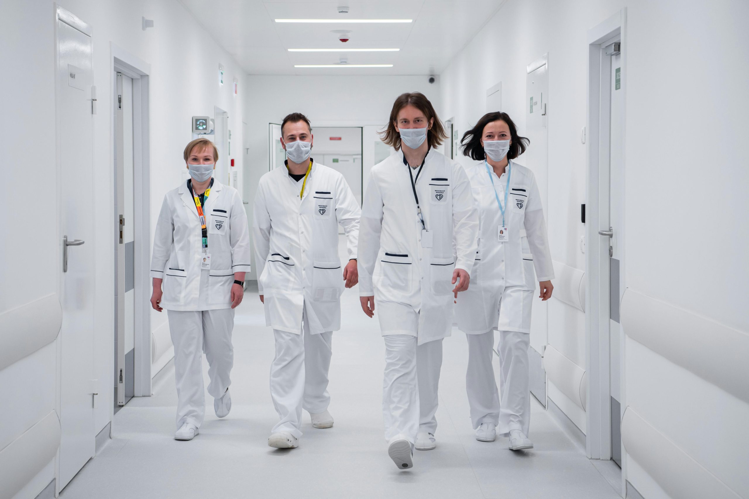 Medical team walking confidently in a hospital corridor, wearing face masks and white coats, symbolizing teamwork and healthcare dedication.